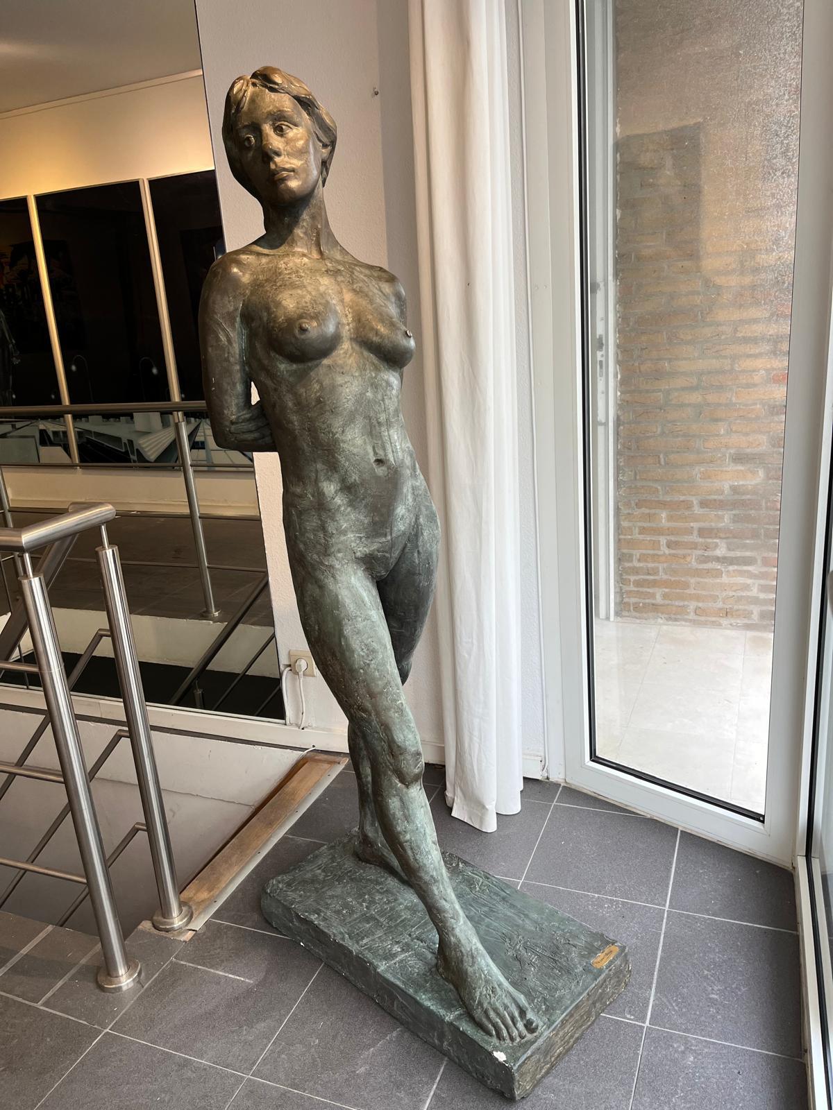 Staande figuratieve sculptuur naast een raam in de galerij